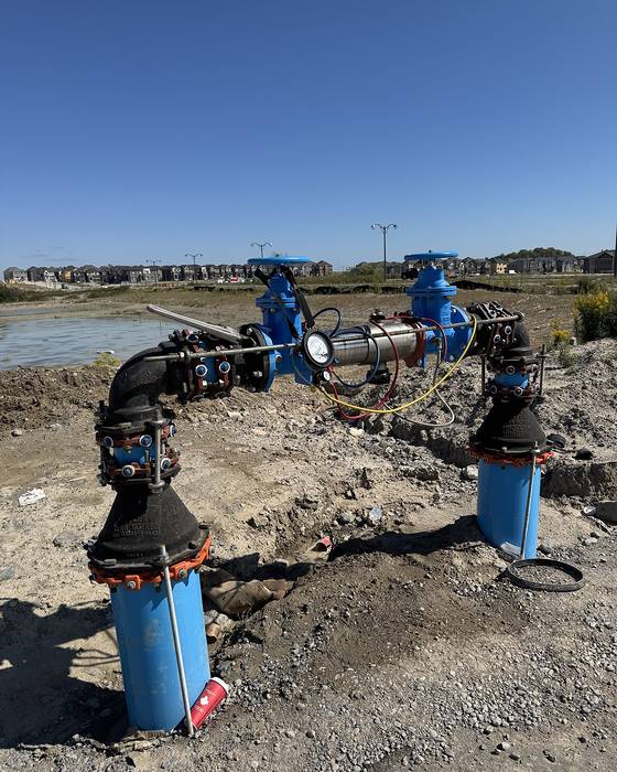 Outdoor backflow preventer assembly on blue pipe at a construction site under a clear sky