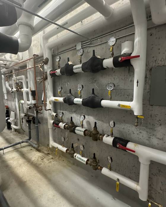 Wall of insulated piping with gauges, balancing and pressure-reducing valves and ball valves