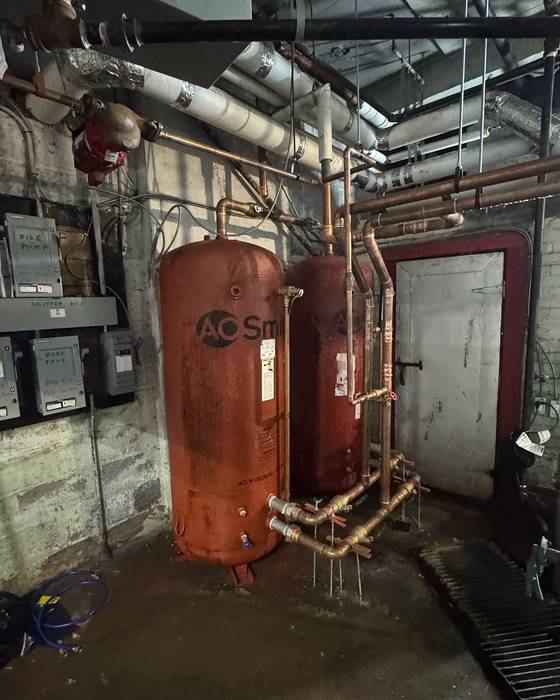 Two large A. O. Smith storage tanks with copper piping in a mechanical room