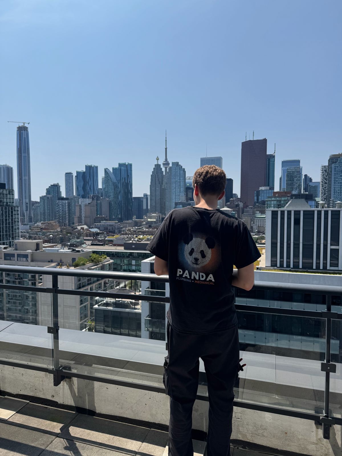 Panda Plumbing & Mechanical team member in a black PANDA shirt looking at the Toronto skyline